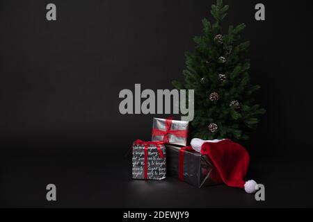 Christmas tree gift boxes and santa hat on black background  Stock Photo