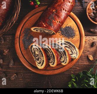 Beigli, slices of Hungarian poppy seed roll on wooden cutting board Stock Photo