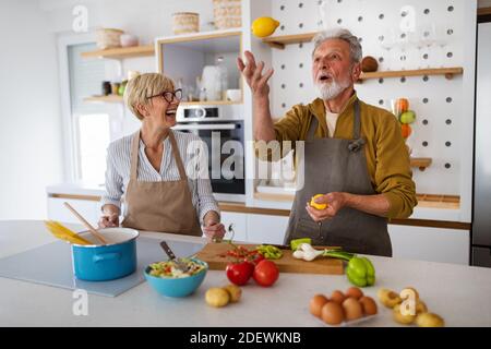 Senior couple having fun, cooking together in home kitchen Stock Photo
