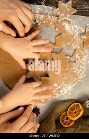 Close-up child and female hands making festive cookies and gingerbread men. Stock Photo
