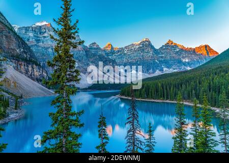Moraine lake sunrise time in summer sunny day. Snow-covered Valley of the Ten Peaks turning red and reflect on turquoise color water surface. Stock Photo