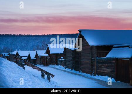 Irkutsk, Russia- 8 January 2019: Winter landscape with traditional wooden houses and colorful sky during sunset in Ethnographic museum Taltci. Stock Photo