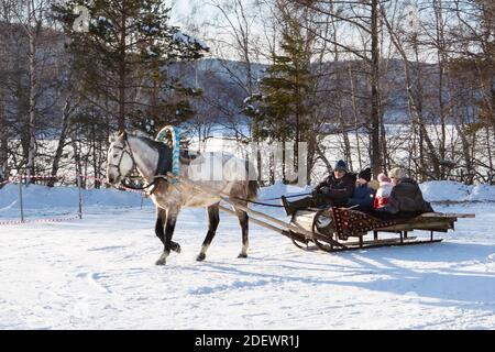 Irkutsk, Russia- 8 January 2019: Christmas sleigh with one horse running on white snow in Ethnografic museum Taltci. People with horse sledge outdoor Stock Photo