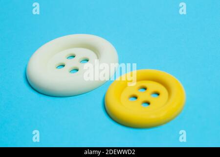 A close-up of two buttons of different sizes and colors on a light blue background. Diversity concept. Stock Photo