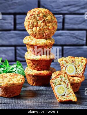 Bacon, Egg and Cheese Breakfast Muffins on a black plate on a wooden table with a brick wall at the background, horizontal view from above Stock Photo