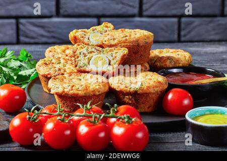 Bacon, Egg and Cheese Breakfast Muffins on a black plate on a wooden table  with ingredients, horizontal view from above Stock Photo