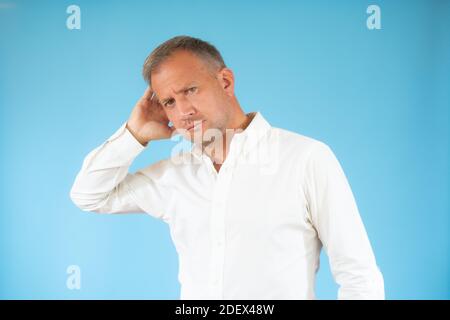 Young man in casual shirt thinking over blue background. Stock Photo