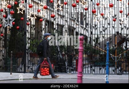 (201202) -- BEIJING, Dec. 2, 2020 (Xinhua) -- A man wearing a mask walks past some Christmas decorations in Paris, France, Nov. 18, 2020. (Xinhua/Gao Jing) Stock Photo