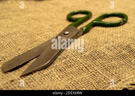Large vintage scissors lie on rough homespun fabric. Close up Stock Photo