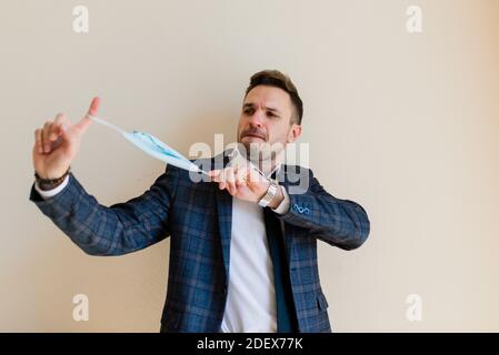 Businessman adjusting protective face mask in hotel room. Stock Photo