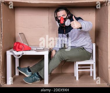 employee works from his own cardboard office to isolate himself from others Stock Photo