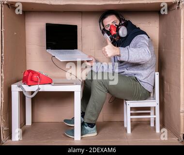 employee works from his own cardboard office to isolate himself from others Stock Photo