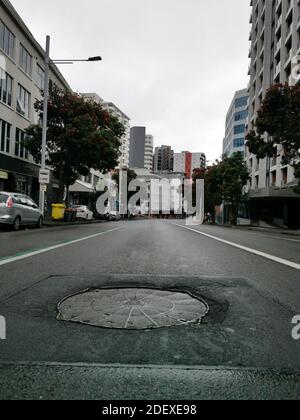 AUCKLAND, NEW ZEALAND - Nov 29, 2020: Low angle view down Anzac Avenue without traffic with sewer hatch in front Stock Photo