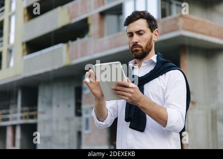Competent engineer looking at tablet while working outdoors Stock Photo