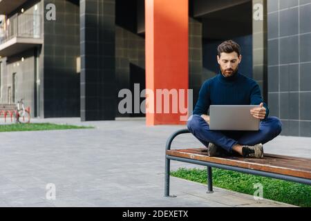Bearded man working on laptop outdoors Stock Photo