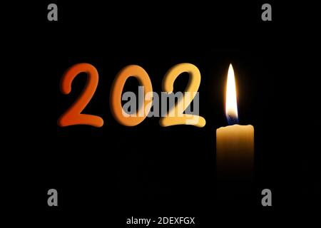 New year 2021 written with a candle flame lightening the year, isolated on a black background. Stock Photo