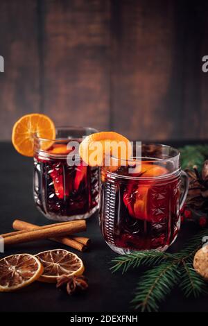 Two glasses of hot mulled wine with fruits and spices on dark background. Winter warming holiday drink. Stock Photo