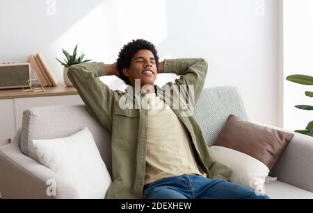 Calm young teen guy relaxing on sofa, napping with closed eyes, feeling peaceful at home, panorama Stock Photo