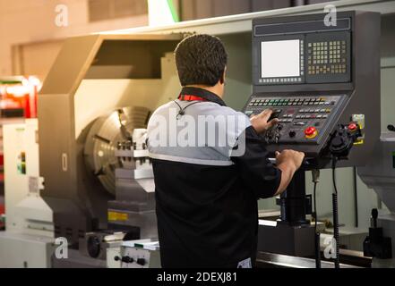 Industrial technician operating CNC lathing machine. Metalworking manufacturing factory Stock Photo