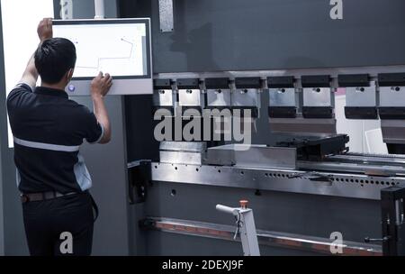 Industrial technician opearting CNC synchronize hydraulic press brake. Metalworking manufacturing factory Stock Photo