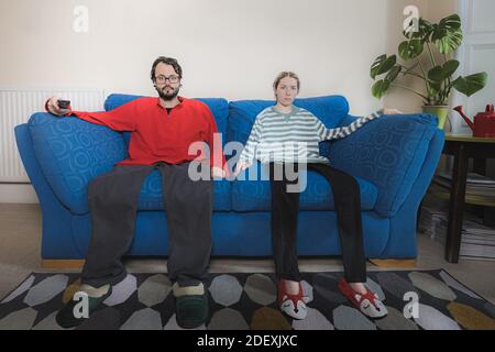 After too much time inside binge watching television this couple have become part of their sofa. Stock Photo