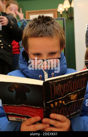 Boswell Book Festival Dumfries House, East Ayrshire, Scotland, UK  A young boy is absorbed in reading his book Stock Photo