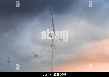 Wind turbines generating green electricity in autumn storm  Stock Photo