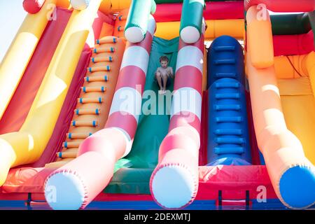 The boy slides down the inflatable slide. Stock Photo