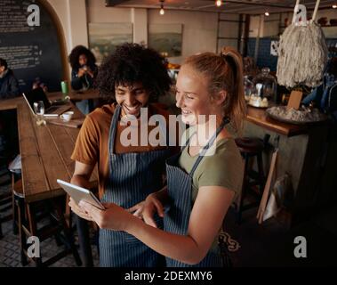High angle view of young cafe owners standing using digital tablet wearing apron Stock Photo