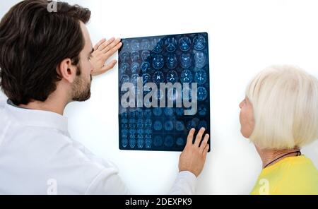 doctor shows to an elderly woman the results of MRI scan of her brain. Diagnostics and treatment of brain diseases, headaches, tumors, and brain cance Stock Photo