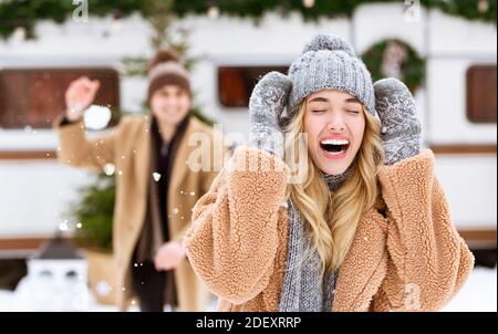 Outdoor Fun. Happy Cheerful Young Couple Throwing Snowballs At Each Other Stock Photo