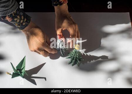 Hands making arrangement of Christmas decorations, handmade with paper using the origami technique Stock Photo