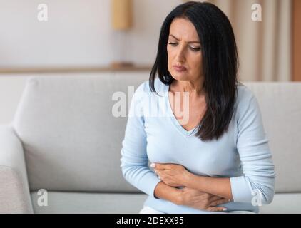 Mature Woman Suffering From Stomachache, Touching Belly Stock Photo
