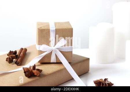 Christmas Gifts Closeup Arranged on White with Candles, Cinnamon Sticks and Anise Stars. Celebration Concept. Stock Photo