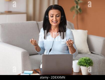 Woman in headset having video call on computer Stock Photo