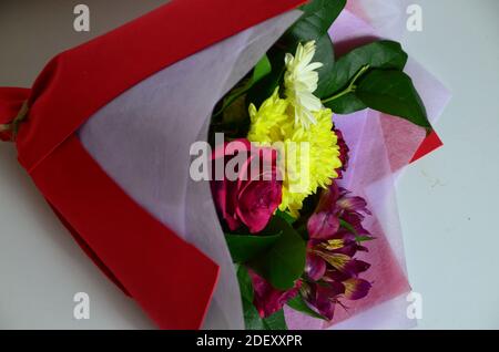 Close-up colorful spring bouquet with many different flowers jelly and white chrysanthemums, burgundy red roses, alstroemeria. Stock Photo