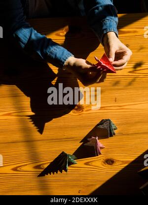 Creating Christmas gifts decorations with Christmas trees. Made with your own hands. Top view of wooden table with female hands. Leisure crafts for wo Stock Photo