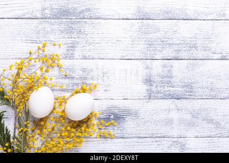 White eggs, mimosa flowers on a wooden table View from above Copy space Stock Photo