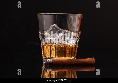 Burning cigar and glass of whisky on black background Stock Photo