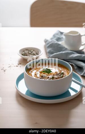 Pumpkin soup with coconut milk and seeds in blue bowl Stock Photo