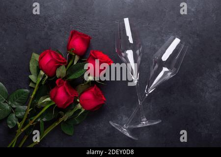 Red rose flowers bouquet, champagne glasses on black stone background Valentine's day greeting card Copy space Top view Stock Photo