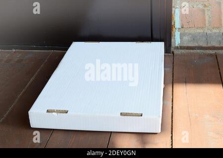 High angle view of pizza boxes and packaging on the floor near the door on the wooden porch of a country house. Stock Photo