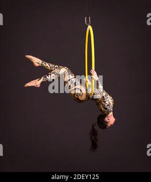 A young woman in a suit with a print performs acrobatic elements in the ...