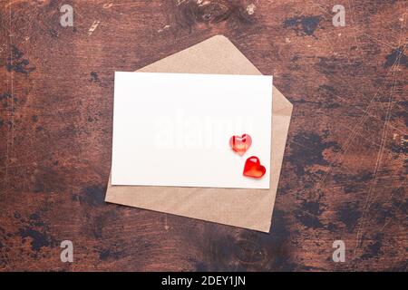 Craft envelope with red hearts on a vintage wooden background Piece of paper Valentine day concept Flat lay Top view Stock Photo