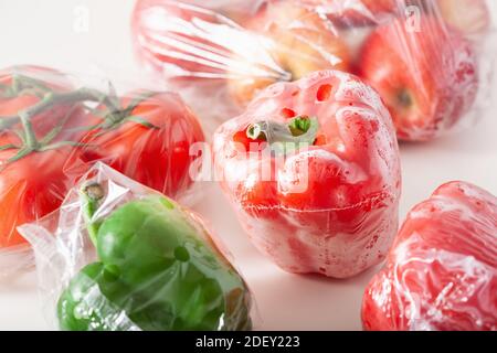single use plastic packaging issue. peppers tomatoes apples vegetables in plastic bags Stock Photo