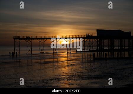 A beautiful moody sunset with reflections in the water and sand be the Pier at Bognor Regis. Stock Photo