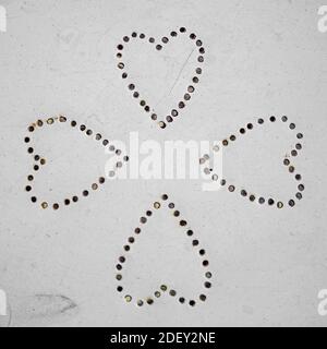four hearts, pointed towards each other, punched  into metal Stock Photo