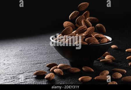 Falling almond nuts on black background with copy space Stock Photo