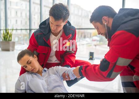 Ambulance crew giving first aid to the faint woman Stock Photo