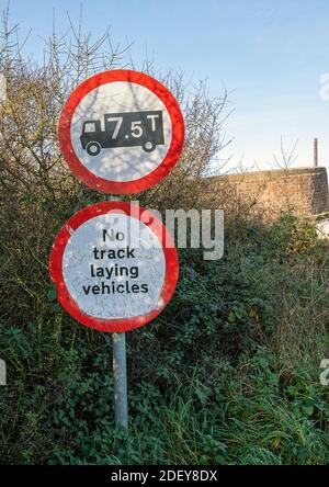 Warning signs for a 7.5 ton limit and no track laying vehicles on approce to a weak bridge Stock Photo